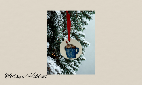Handcrafted Christmas ornament for home featuring a sublimation glass design of a blue mug with whipped cream hanging on a snowy pine tree