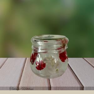 Handmade resin home decor jar with embedded red and white flowers on wooden surface