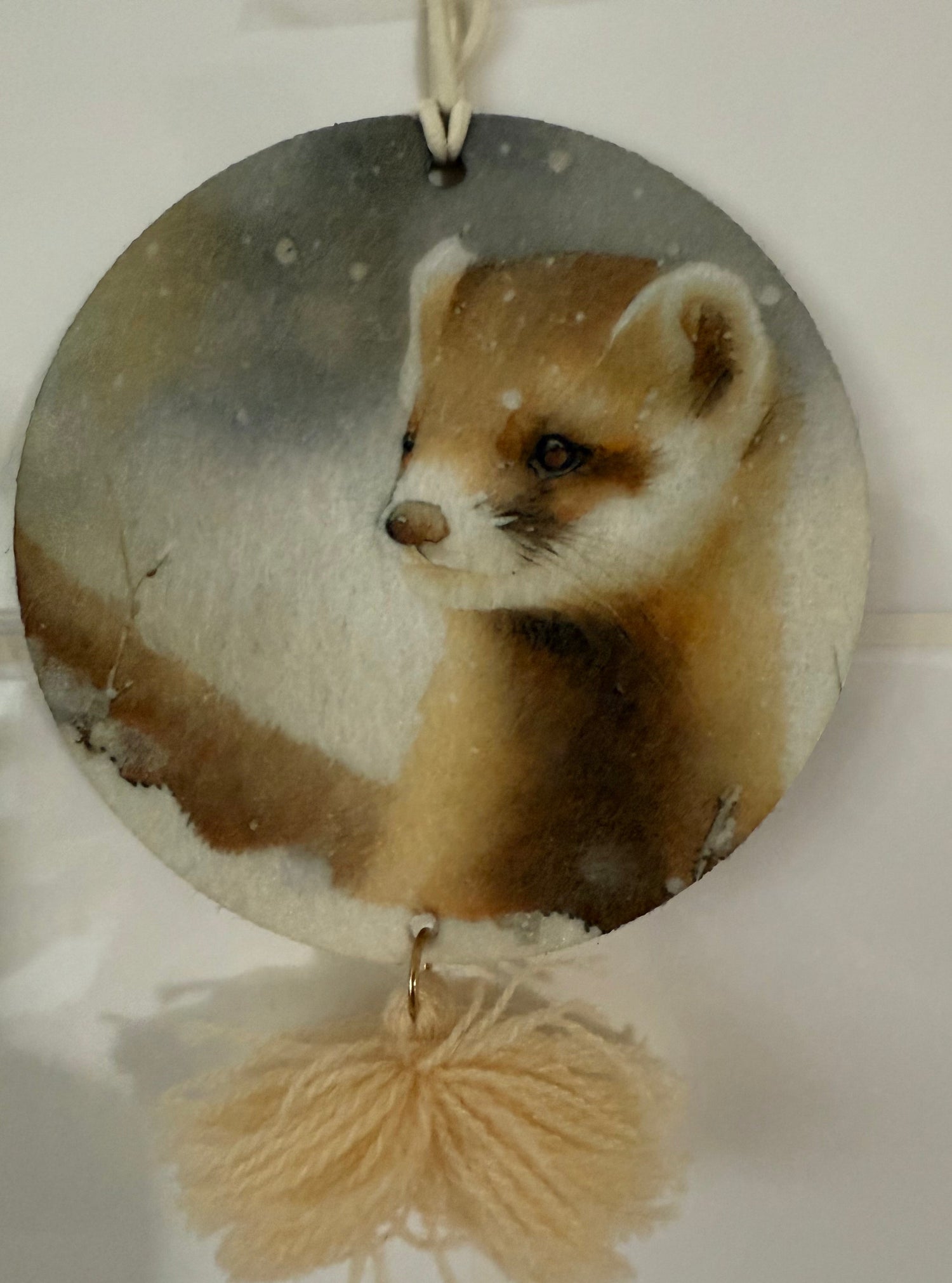 Round hanging wax melt with a painted weasel design and a fluffy tassel unique home fragrance gifts