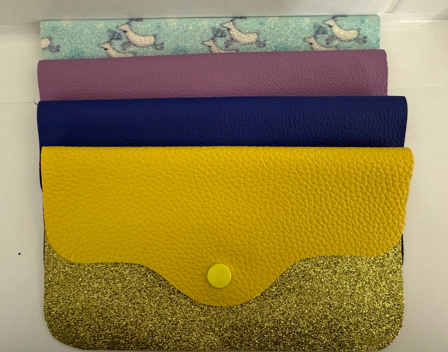 Artisan fashion accessories featuring handcrafted leather wallets in yellow, blue, purple, and patterned designs