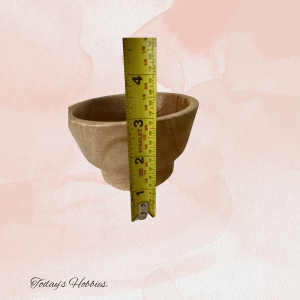 Handmade small oak bowl by Today's Hobbies with a measuring tape showing its size on a pink background