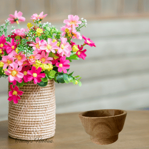 Handmade small oak bowl displayed next to a woven vase with pink and yellow flowers on a wooden table